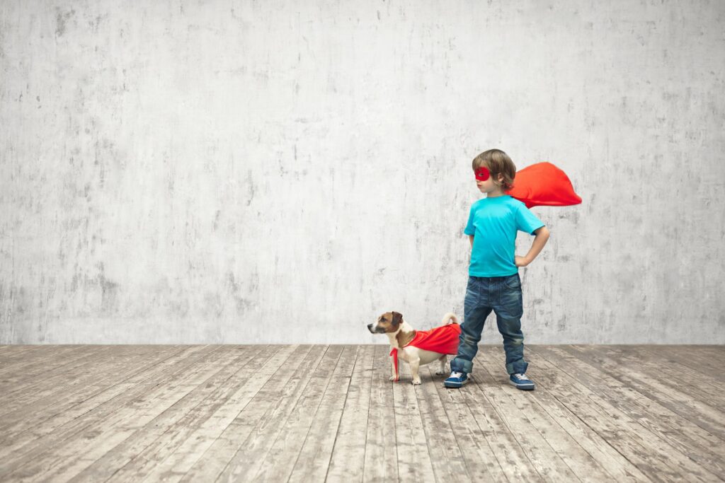 Kind und Hund mit Superhelden-Umhängen.