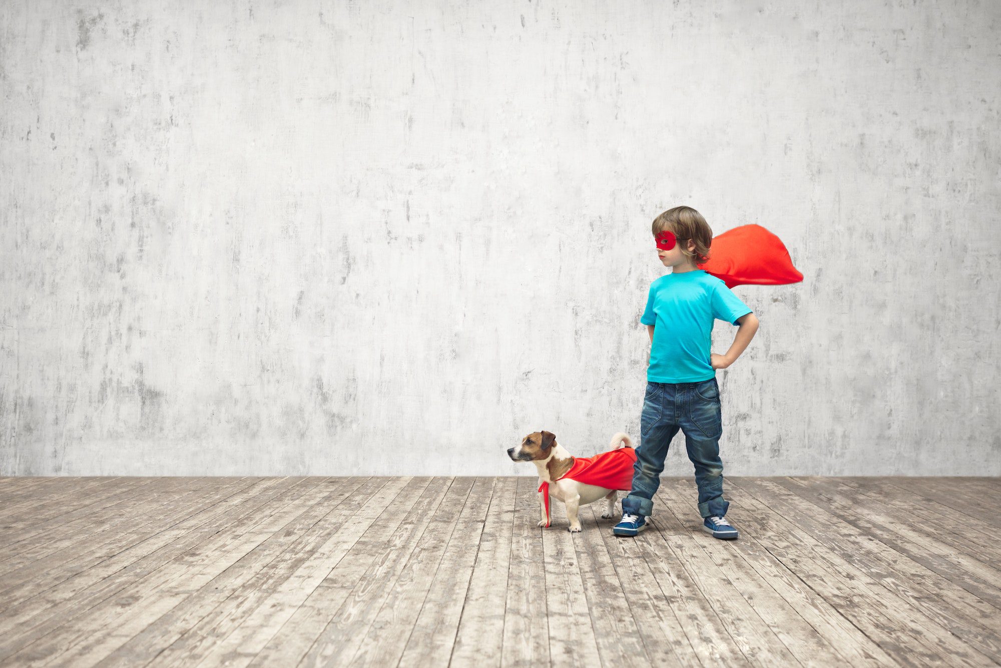 Kind und Hund mit Superhelden-Umhängen.